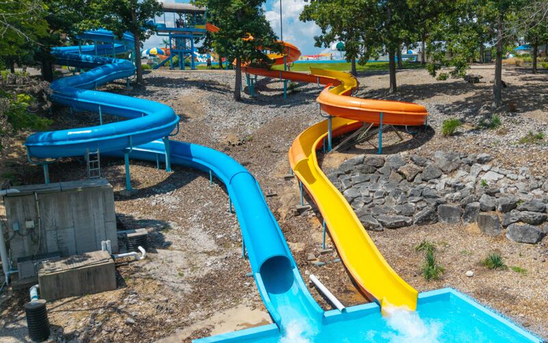 Twisting blue and yellow flume water slides curving down through the trees into a splash pool